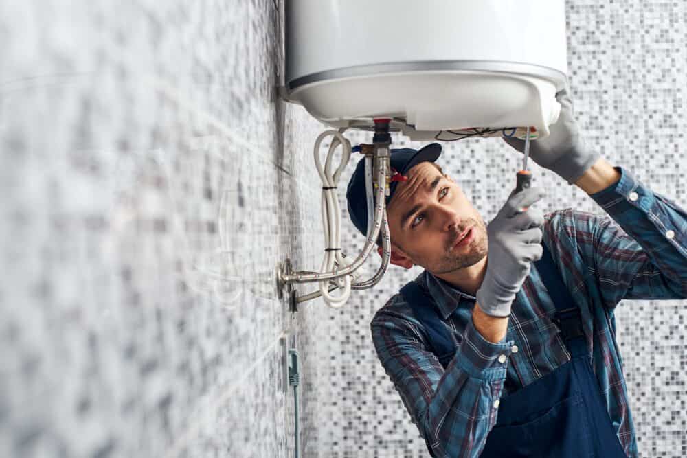 HVAC technician working on a water heater in a New Jersey home during the winter and fall